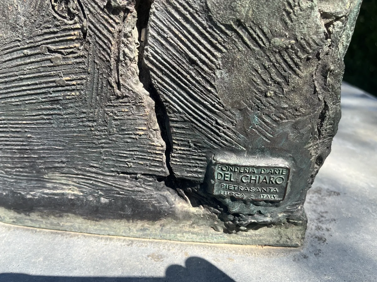 Angled close view of the Fonderia d'Arte Del Chiaro foundry mark cast into the base of Tindaro Screpolato — the small bronze plaque set against the deeply scored casting surface