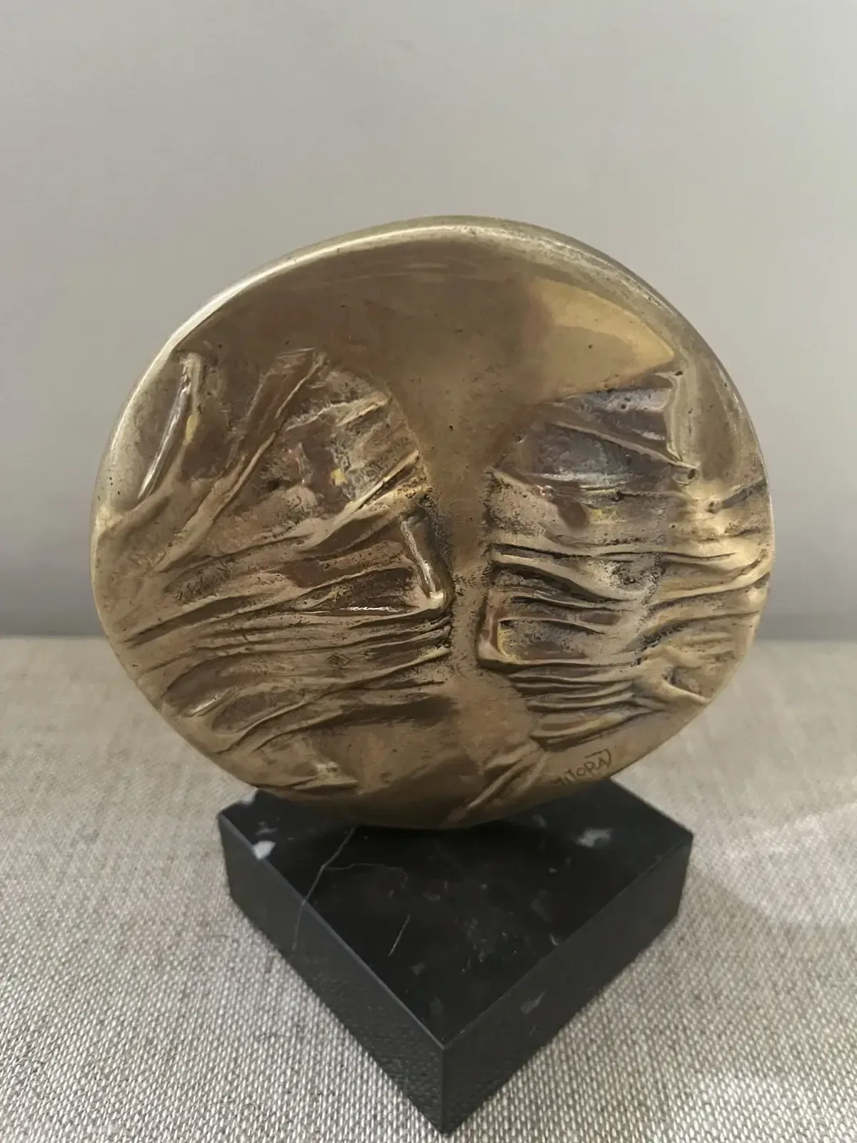 La Conversation — Igor Mitoraj, obverse two veiled profiles, warm gold patina on black marble base, lower angle