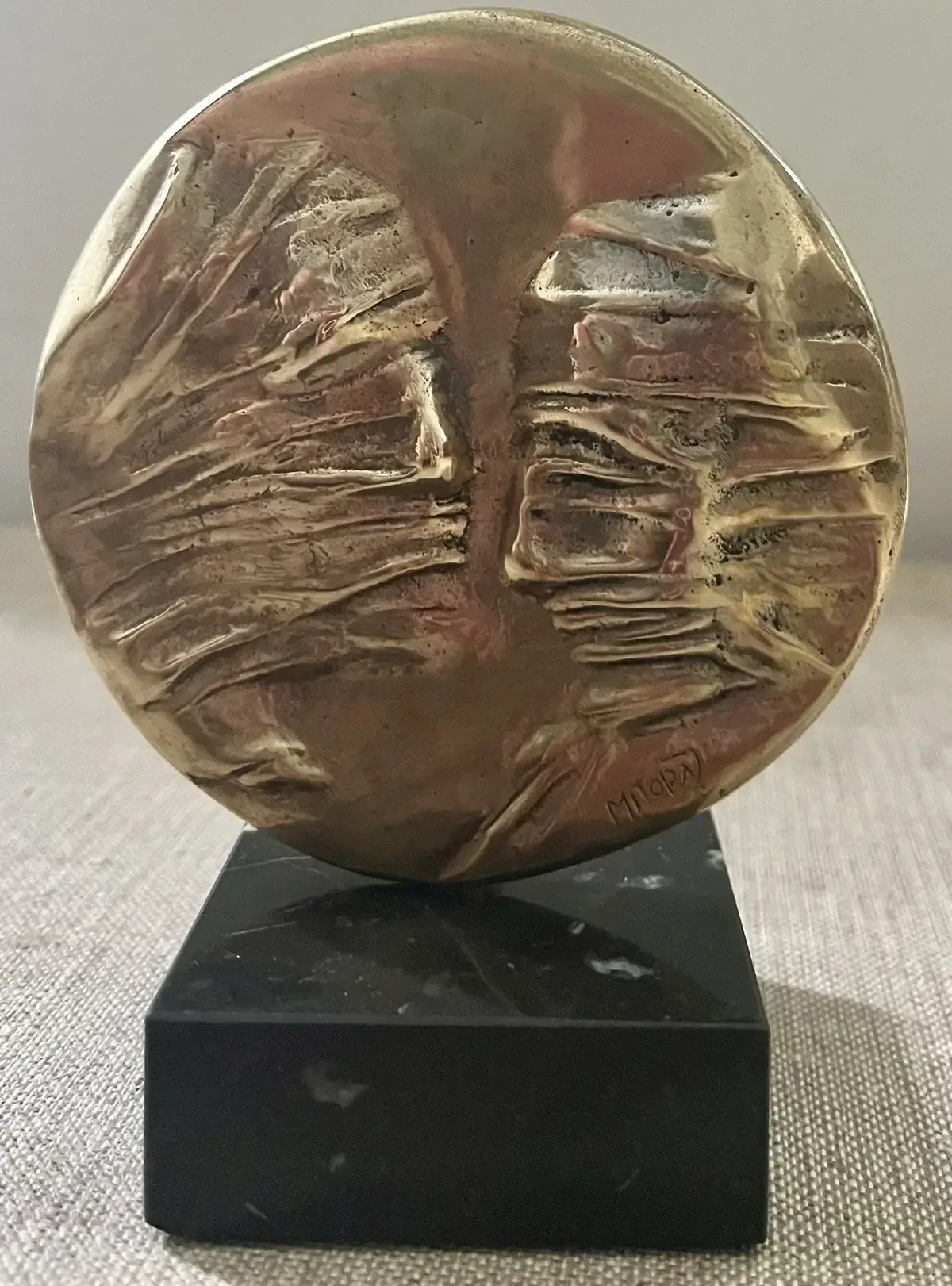 La Conversation — Igor Mitoraj, obverse two veiled faces, warm gold patina on black marble base, centred portrait