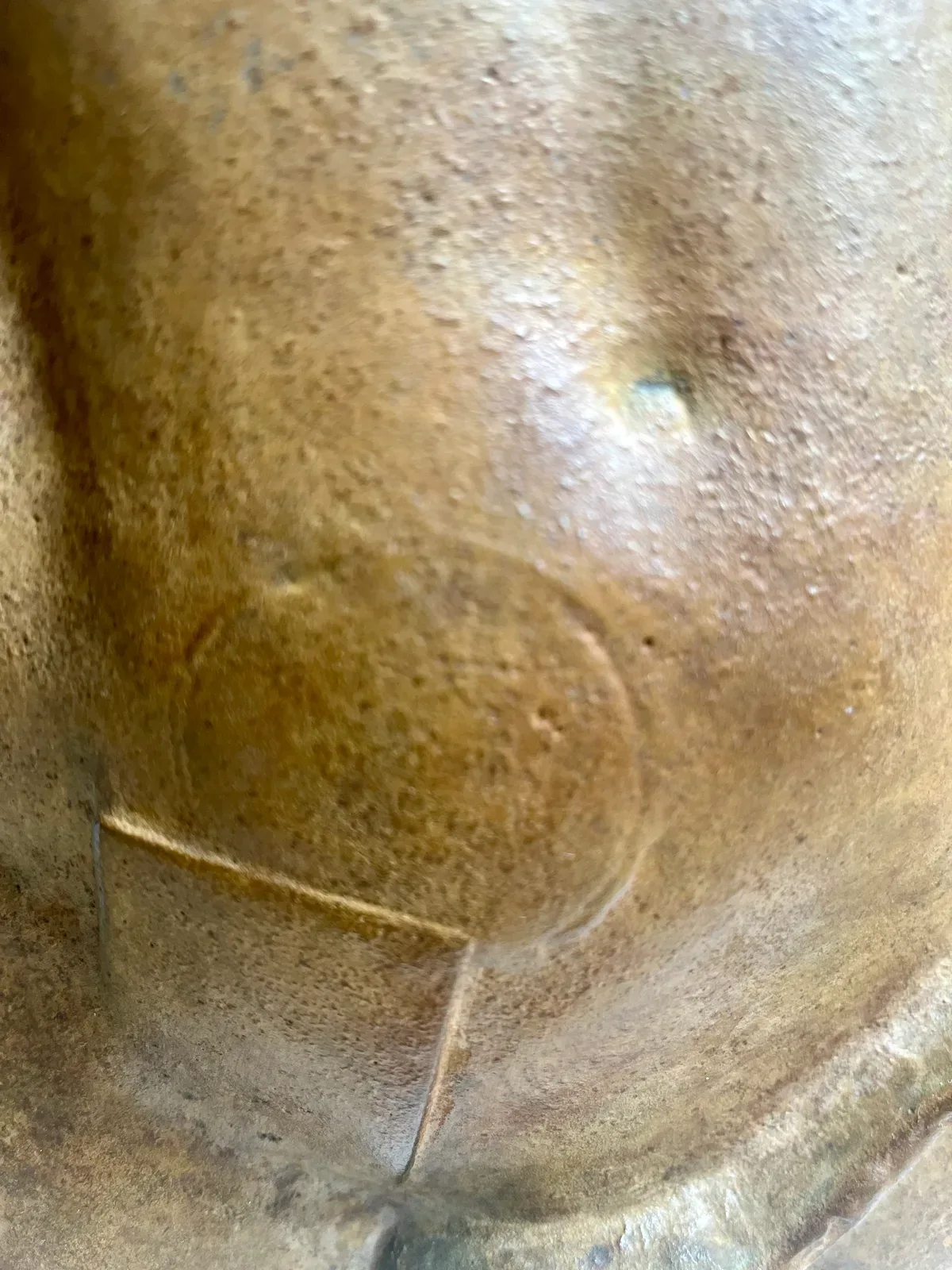 Persée (1988) — Igor Mitoraj, extreme close-up macro of the chest surface and inset detail, showing the warm brown patina texture, casting porosity, and the characteristic Mitoraj rectangular cutout, private collection Warsaw