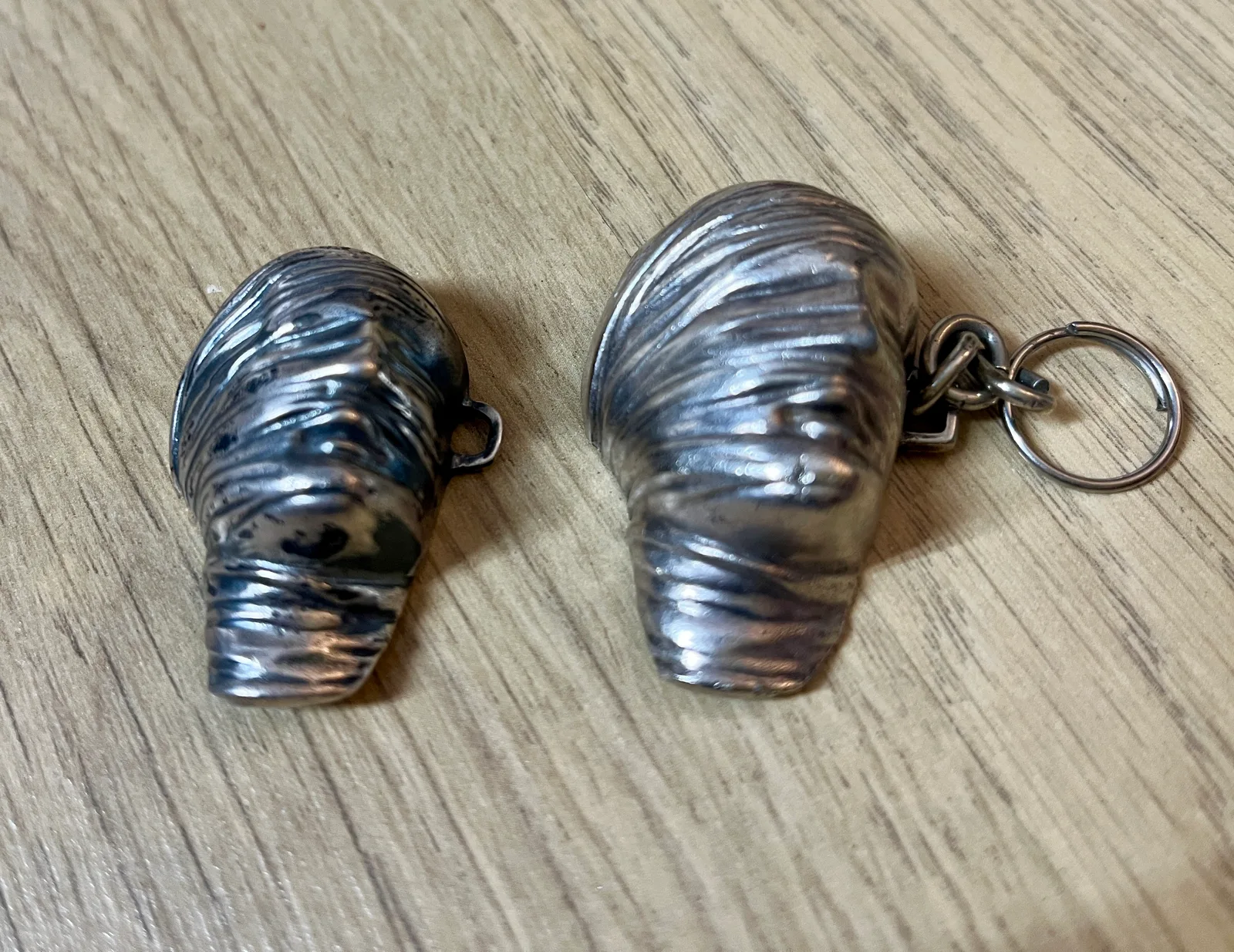 Testa Addormentata — pair of Mitoraj Amnesty International silver pendants at alternate angle, keyring visible