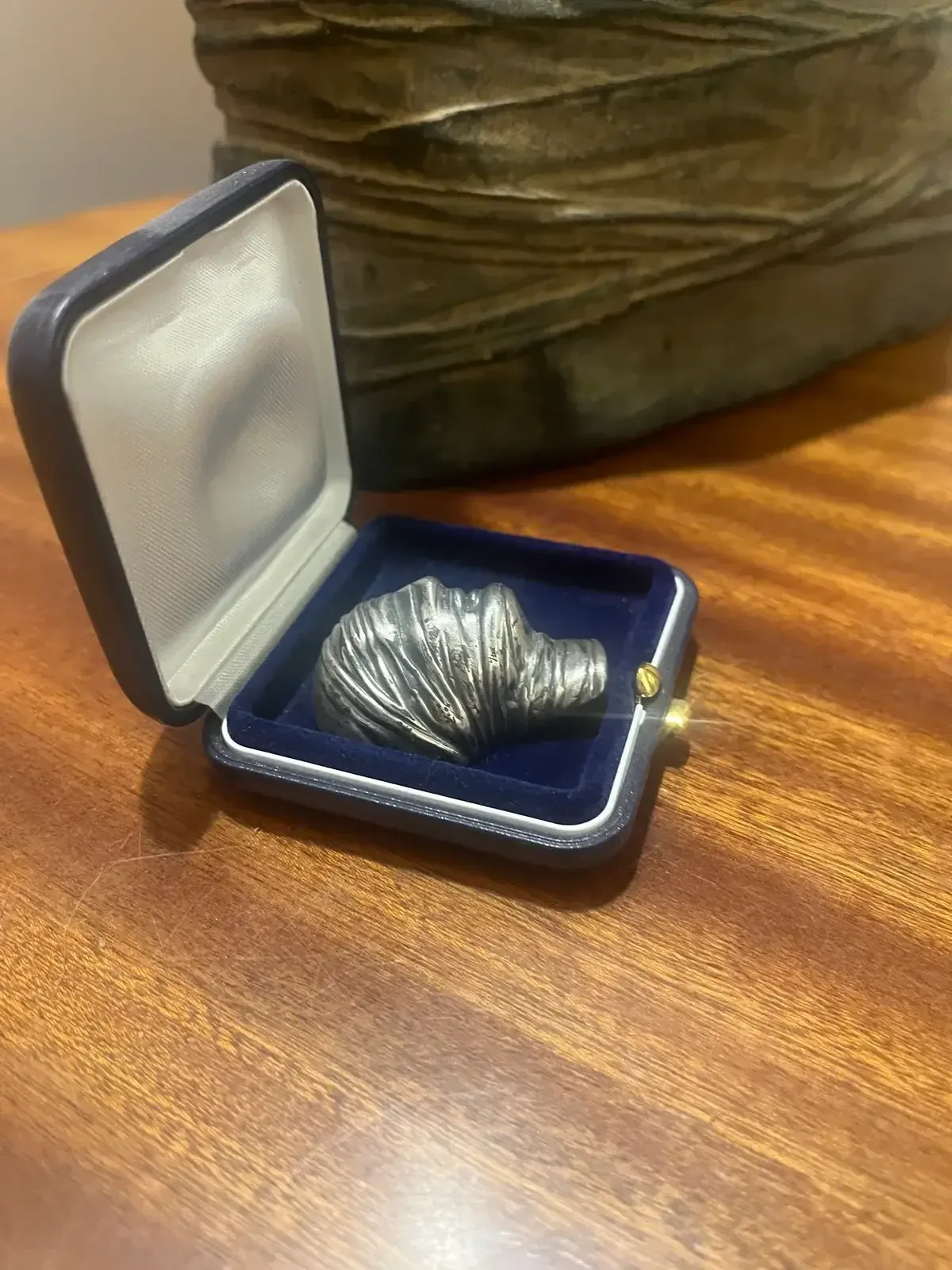Testa Addormentata — silver pendant in box, Mitoraj bronze sculpture in background